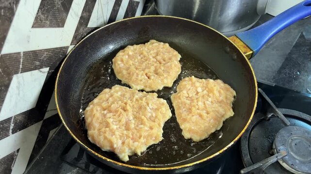 Hands shape a portion of seasoned ground chicken into a patty over a glass bowl.