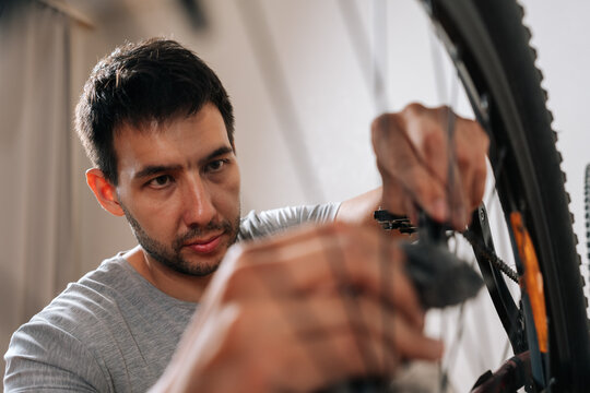 Skilled handyman engaged in bicycle maintenance. Close-up with selective concept of face concept of concentration. Hands in motion blur suggest active repair work.
