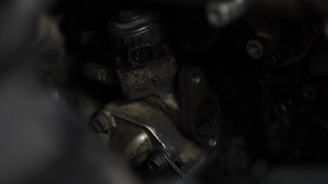 A close-up view shows a dirty car EGR valve or sensor assembly with an open mounting flange inside a dark engine bay.