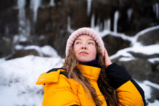Winter portrait of woman in insulated yellow jacket in mountains, outdoor lifestyle, travel, adventure and nature concept.