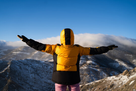 Back view of mountaineer on snowy ridge with raised arms, success, achievement, freedom and mountain adventure concept.