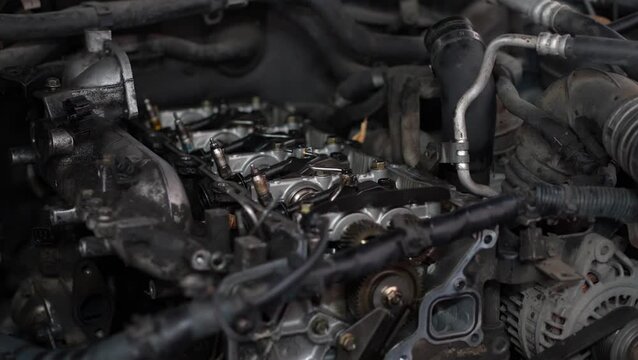 An opened cylinder head of an internal combustion engine exposes camshafts, a timing gear sprocket, and fuel injector lines under repair.