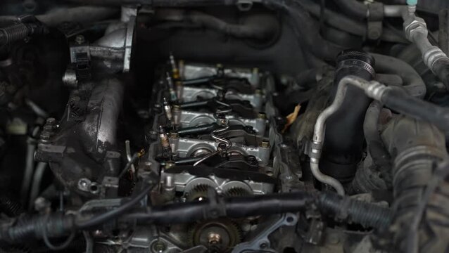 An opened cylinder head of an internal combustion engine exposes camshafts, a timing gear sprocket, and fuel injector lines under repair.