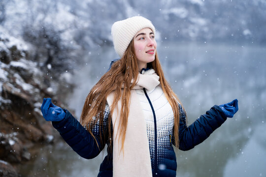 A woman is meditating outdoors near a winter lake, breathing in fresh air and practicing mindfulness, taking care of herself, and embracing the concept of emotional wellbeing and a wellness lifestyle.