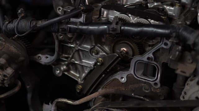 A close-up view shows a metal bracket or guide tool bolted near an internal gear mechanism inside an open car engine block.