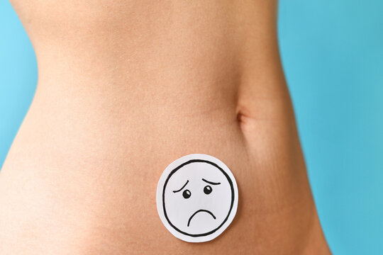 Sad  face on woman abdomen symbolizing menstrual pain, endometriosis, fertility issues and reproductive health problems in fornt of blue background