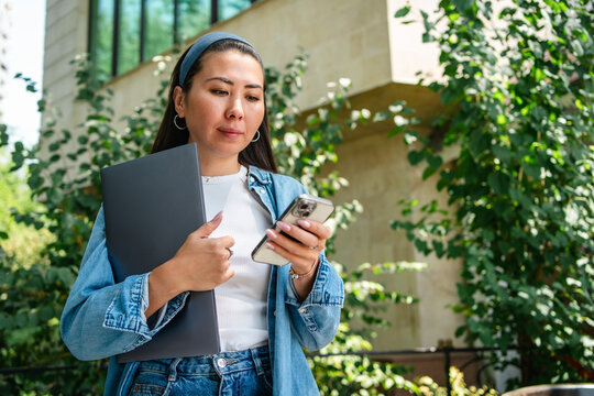 Student use smartphone while holding folder on campus