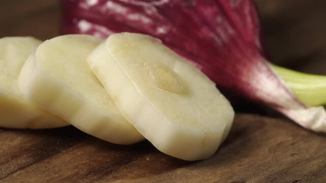 Macro shot of fresh sliced garlic cloves slowly moving on a wooden surface under studio lighting.