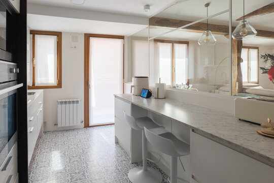 Modern white kitchen with breakfast bar in bright apartment