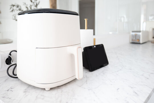 White air fryer on marble kitchen counter in modern apartment
