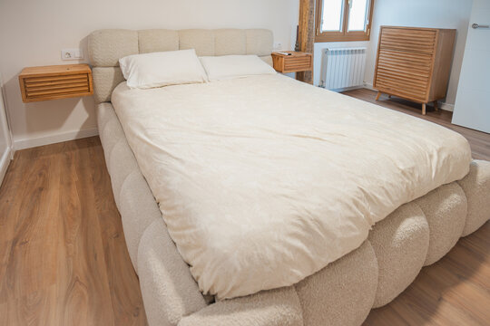 Modern apartment bedroom with upholstered bed and wood furniture