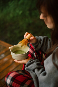 Woman prepare matcha tea on a peaceful summer morning