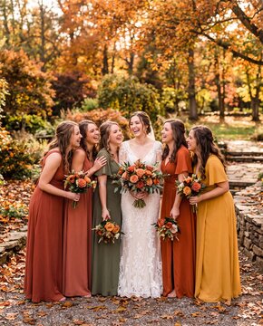 Bride and bridesmaids in autumn gowns laughing outdoors