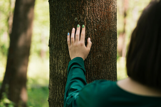 Woman touching tree trunk in a peaceful forest