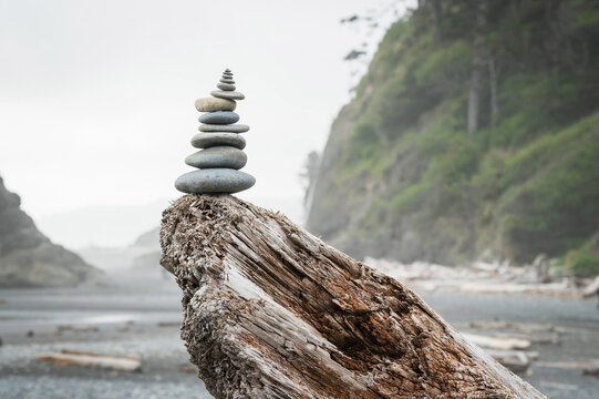 A cairn of balanced stones on a driftwood log.  Dramatic coastline at Ruby Beach in the Olympic National Park.  Washington State, USA.