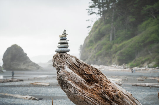 A cairn of balanced stones on a driftwood log.  Dramatic coastline at Ruby Beach in the Olympic National Park.  Washington State, USA.