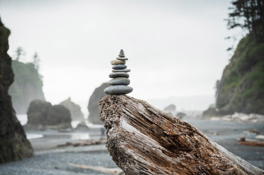 A cairn of balanced stones on a driftwood log.  Dramatic coastline at Ruby Beach in the Olympic National Park.  Washington State, USA.