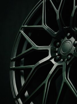 Close-up of Modern Matte Black Alloy Car Wheel Rim with Intricate Spoke Design on Dark Background
