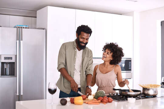 Couple, laugh and cooking in kitchen with help, healthy food and bonding together for lunch recipe. Married, African people and happy in home with meal preparation, funny conversation and nutrition.