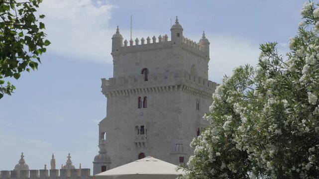 Torre de Belem in Lisbon Portugal framed by white oleander flowers under a bright summer sky