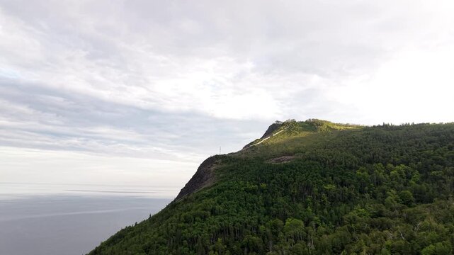 Aerial view of mountain peak lookout building overlooking coastal waters in Mont Saint-Pierre Gaspesie Quebec Canada drone footage