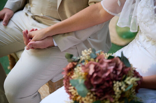 Bride and groom hold hands beside wedding bouquet