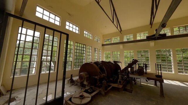 A tour through the historic Pozo de San Fernando coal mine building in Aller, Asturias, showing industrial machinery and mountain views. Suitable for historical and industrial documentaries.