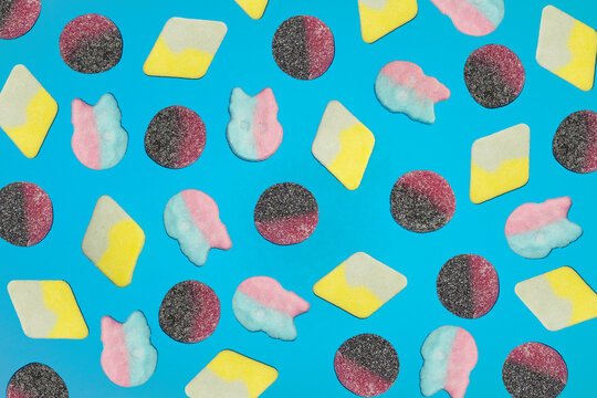 Assorted gummy candy scattered on bright blue background