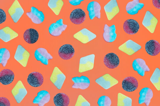 Assorted gummy candy mix on vibrant orange background