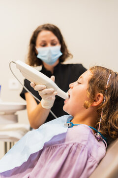 Dentist using intraoral scanner on young patient's mouth