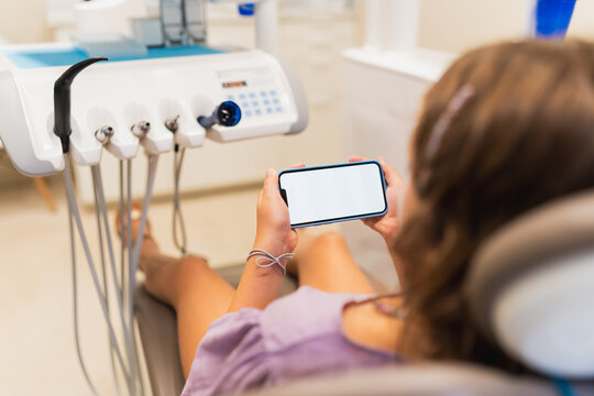 Patient holding smartphone blank screen in dental clinic