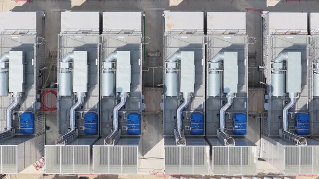 Rows of metal cooling equipment sit on a flat surface at a Data Center during the day to keep large computer servers at a stable temperature for efficient operation and data management performance