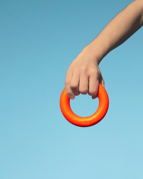 Hand hold orange ring against blue background