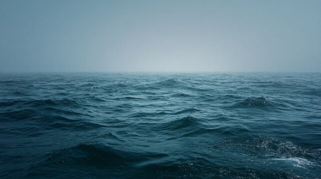 A serene and tranquil wide cinematic shot of an unremarkable empty ocean surface, capturing the subtle waves and misty horizon, evoking a sense of calm and introspection in a muted color palette of bl