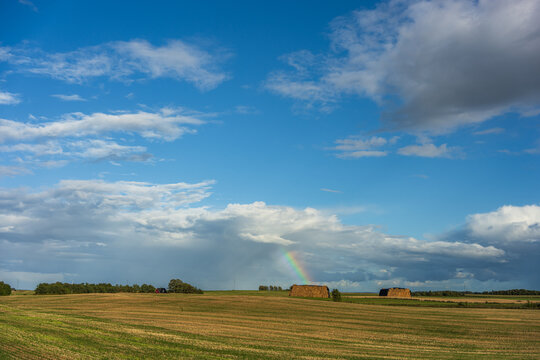 Vibrant Rainbow Piercing Through Storm Clouds Over Harvested Field