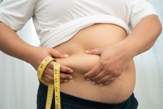 Asian woman use hand to squeeze fat belly big size overweight and obesity.