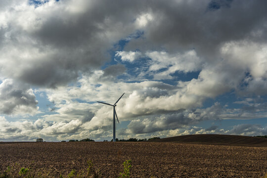 Wind Turbine in Rural Field Under Dramatic Cumulus Sky