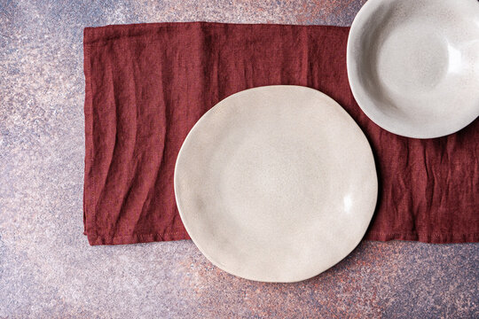 Minimal ceramic table setting with burgundy linen napkin