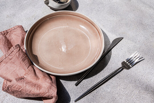 Pink ceramic plate with cutlery and linen napkin