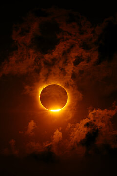 Solar eclipse with fiery corona against dark cloudscape