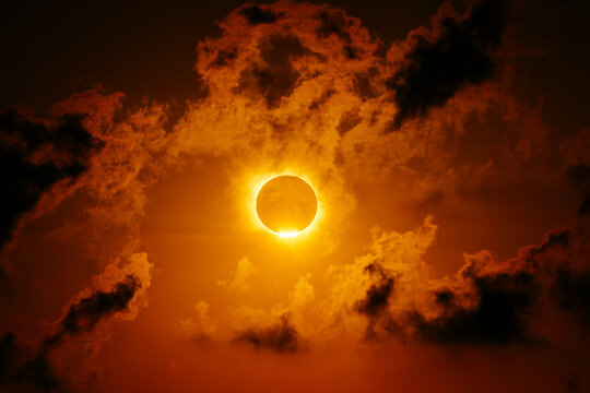 Solar eclipse with fiery corona and dark cosmic clouds