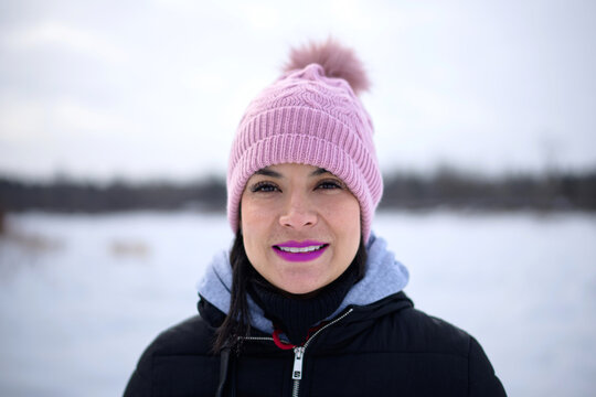 Happy woman in pink beanie portrait in winter snow