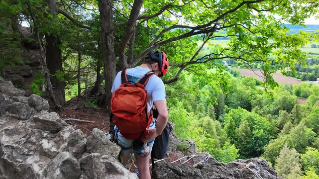 Rock climber rappelling down cliff edge at Rattlesnake Point Conservation Area in Ontario, Canada