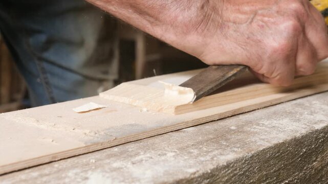 Woodworker chisels bevel on plank end for scarfing plank