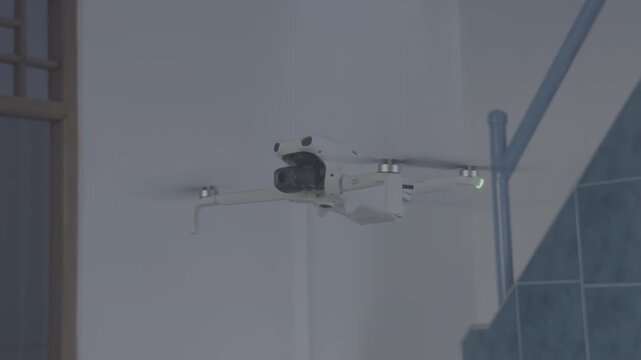 White camera drone hovering indoors for 15 seconds. Shot in Apple Log profile with flat color. HEVC H.265 codec. Professional footage for color grading. Blue stairs and white wall background