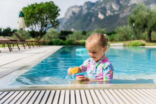 Smiling toddler girl playing in a swimming pool at a mountain resort