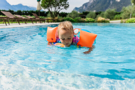 Little girl with floaties learning to swim in a pool