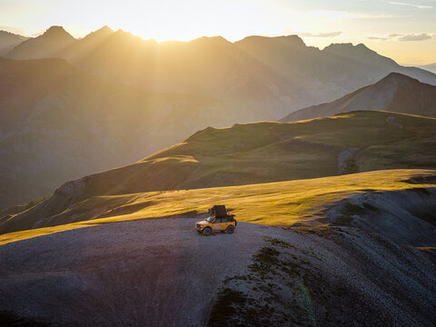 Overlanding vehicle on a remote mountain pass at sunrise