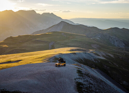 Off road vehicle on a scenic mountain ridge at golden hour