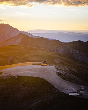 Off road vehicle with rooftop tent on mountain peak at sunset